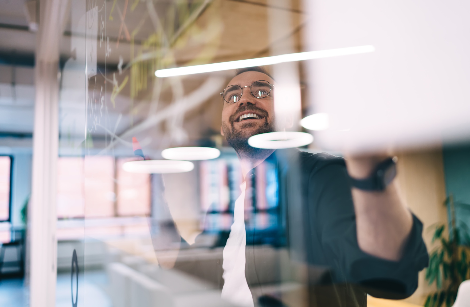 Smiling man looking at glass wall in modern office
